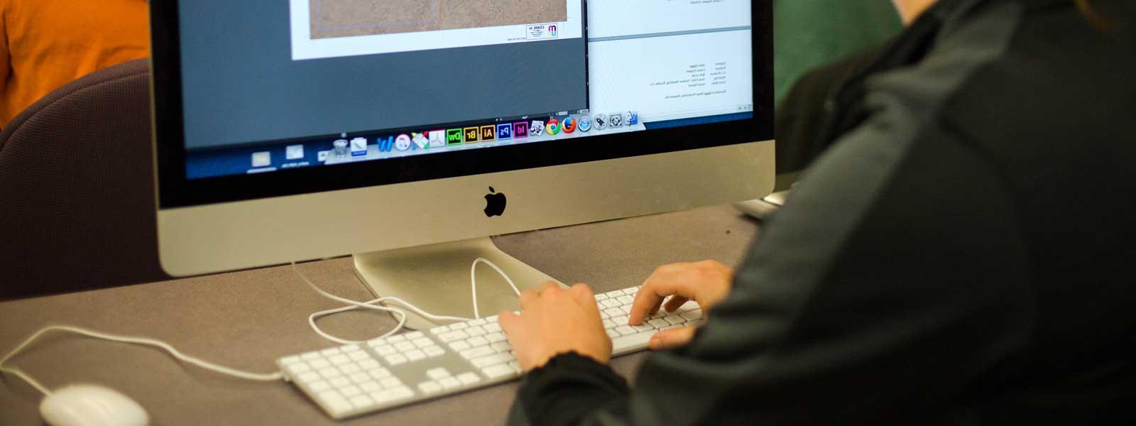 students working on graphic design projects on large Mac computers